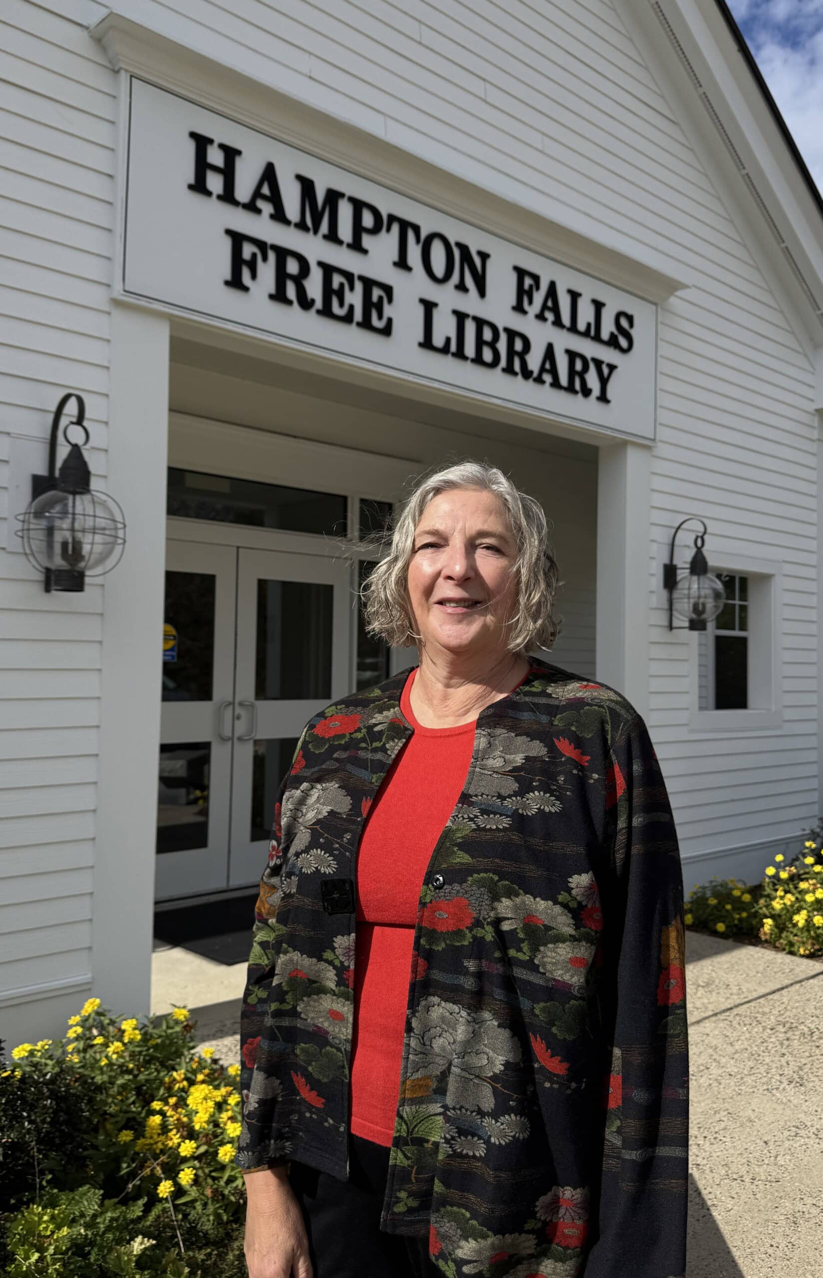 a woman standing in front of the hampton falls free library.