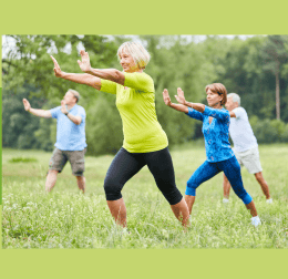 four adults practicing qi gong outdoors in a grassy garden, with the text "qi gong in the library garden" on a green background.